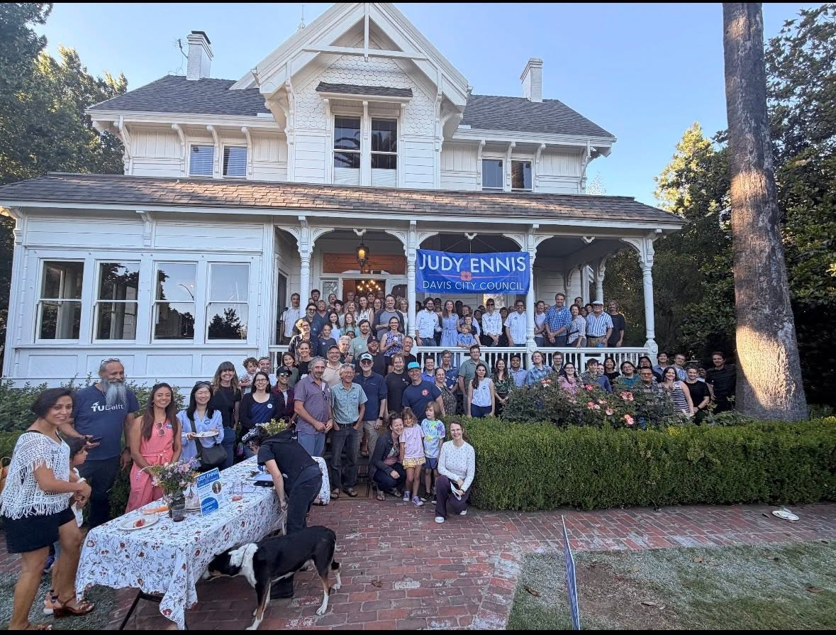 A large crowd of supporters gathered on a Davis porch beneath the Judy Ennis banner