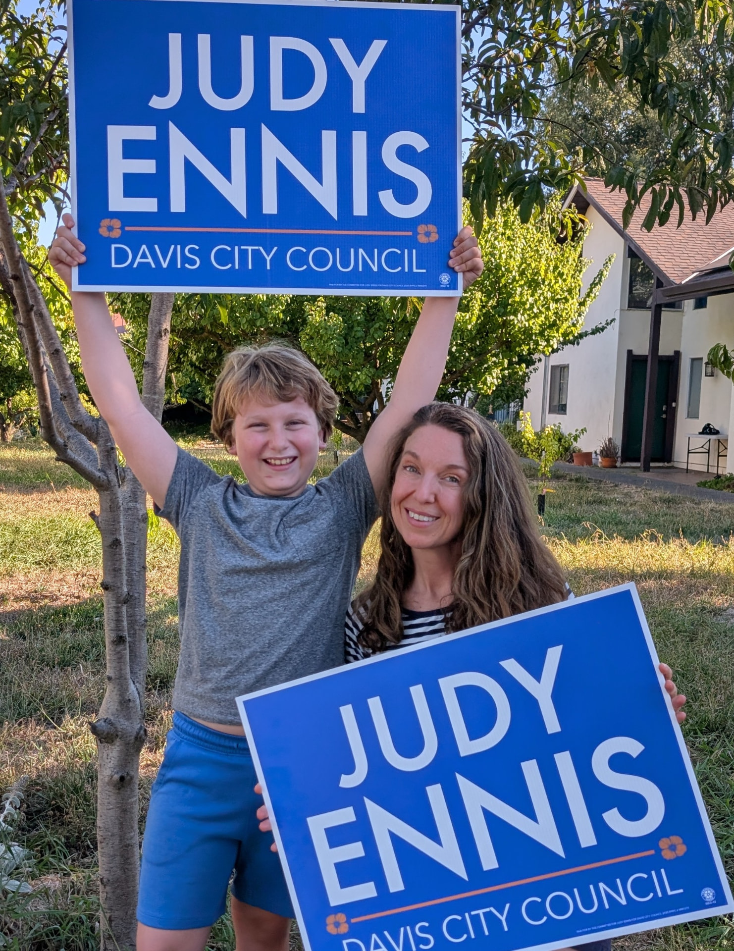 Judy and a young supporter holding Judy Ennis for Davis City Council yard signs.