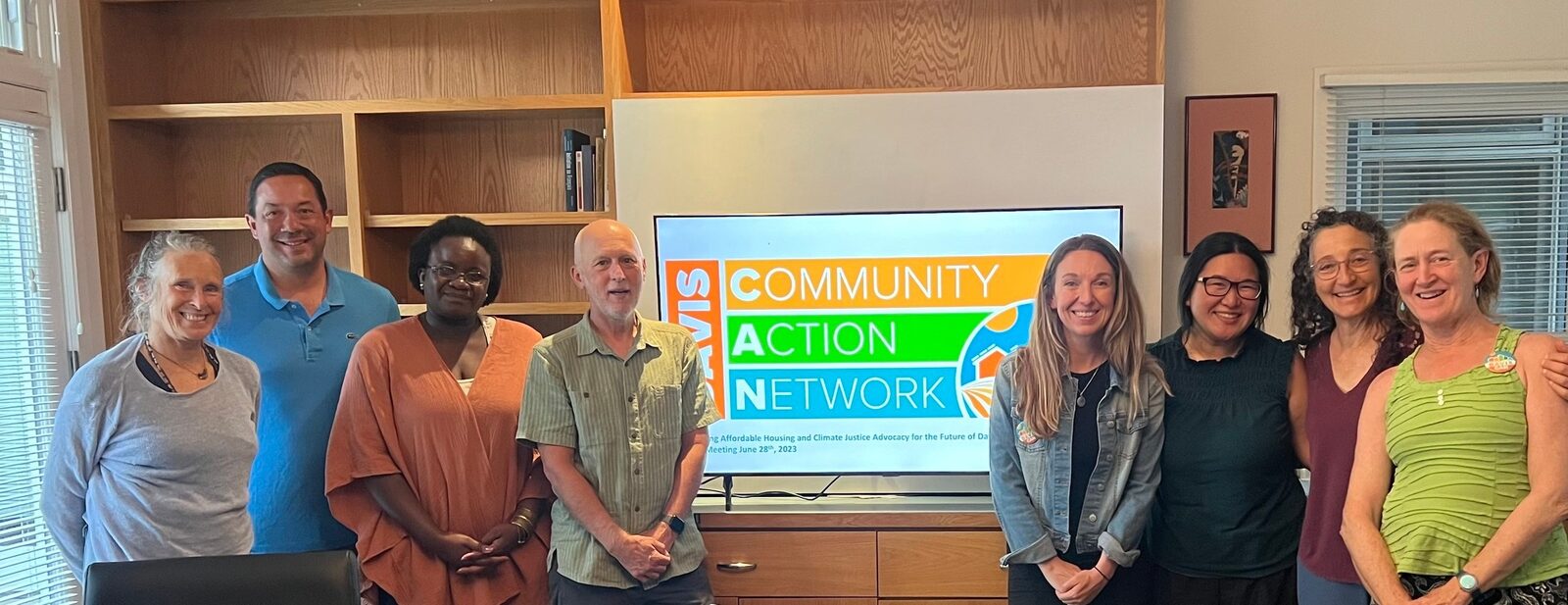 Judy with the DCAN team in front of a Davis Community Action Network sign